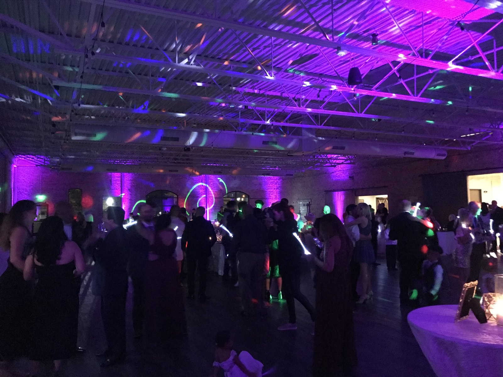 A full dance floor under purple wash lighting with colored patterns across the ceiling