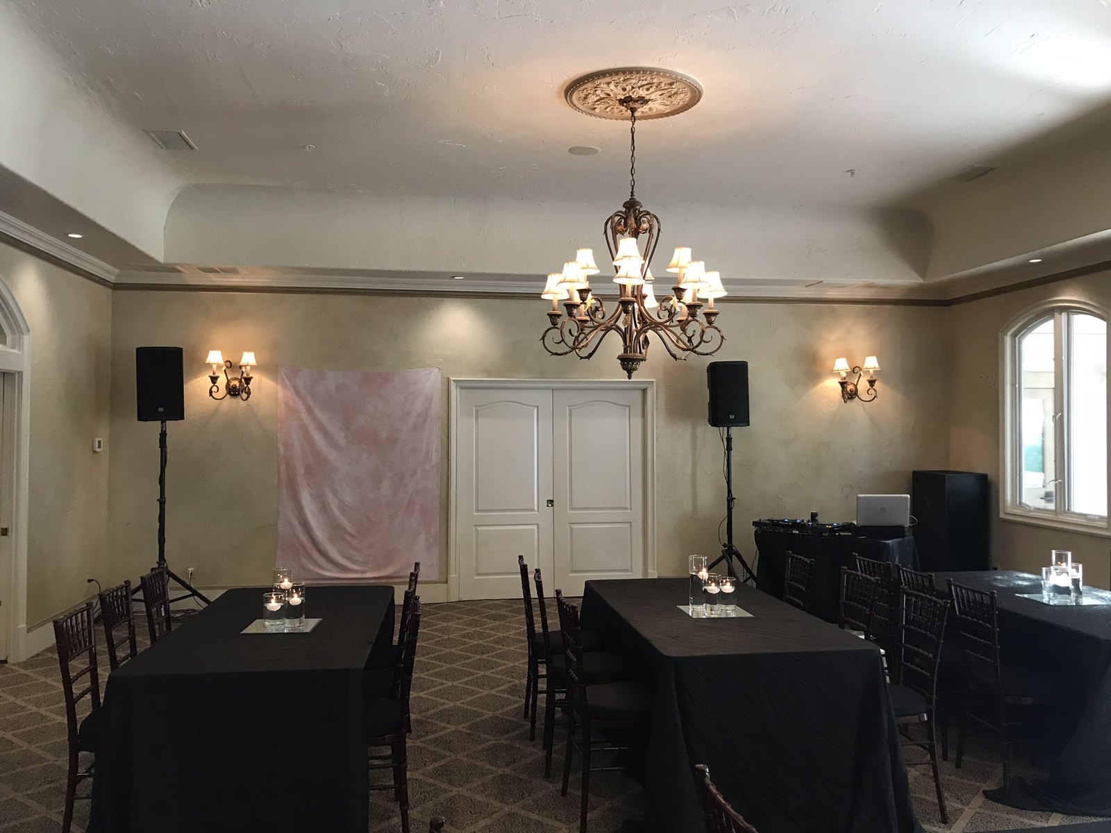 Speaker tops on stands at the front of a private dining room set with long tables