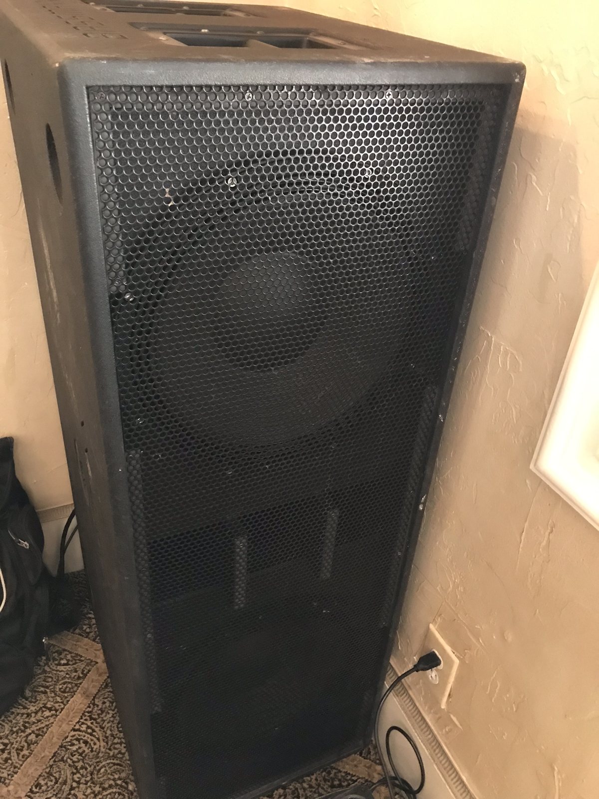 A single subwoofer cabinet standing against a wall before an event