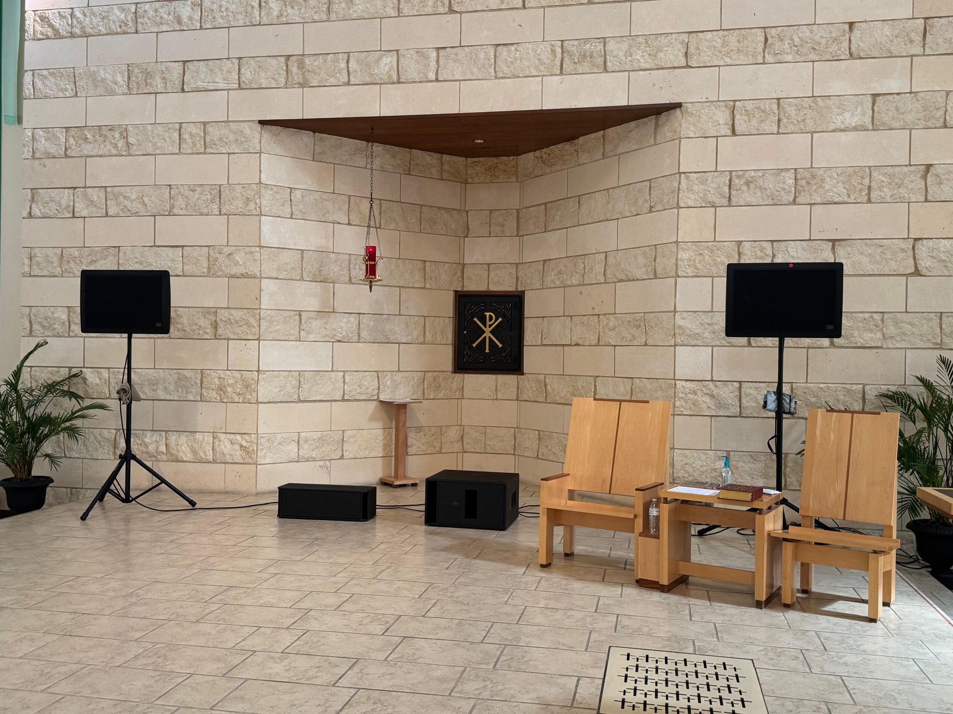 Two DML500 flat panel speakers on stands and two subwoofers on the floor in front of a church altar