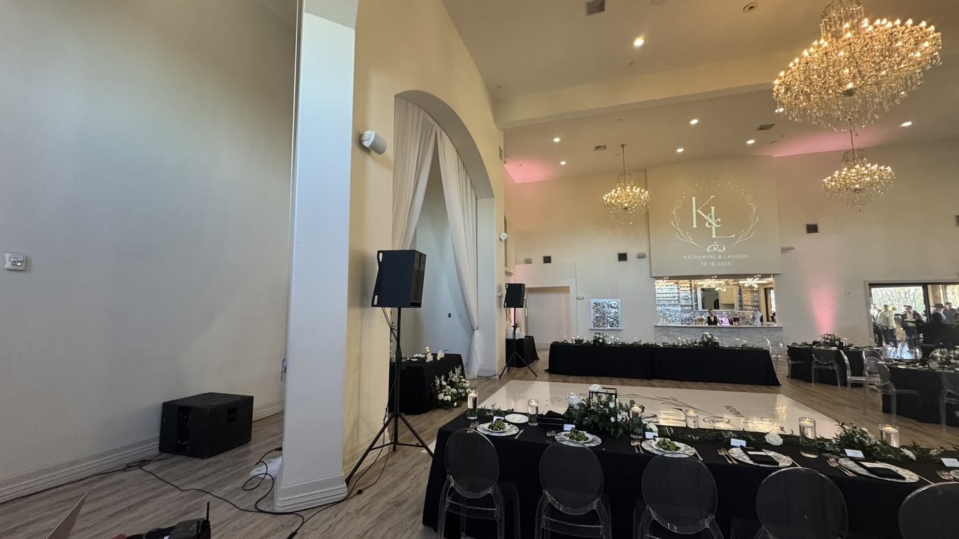 A projected monogram on a reception wall above tables set for dinner