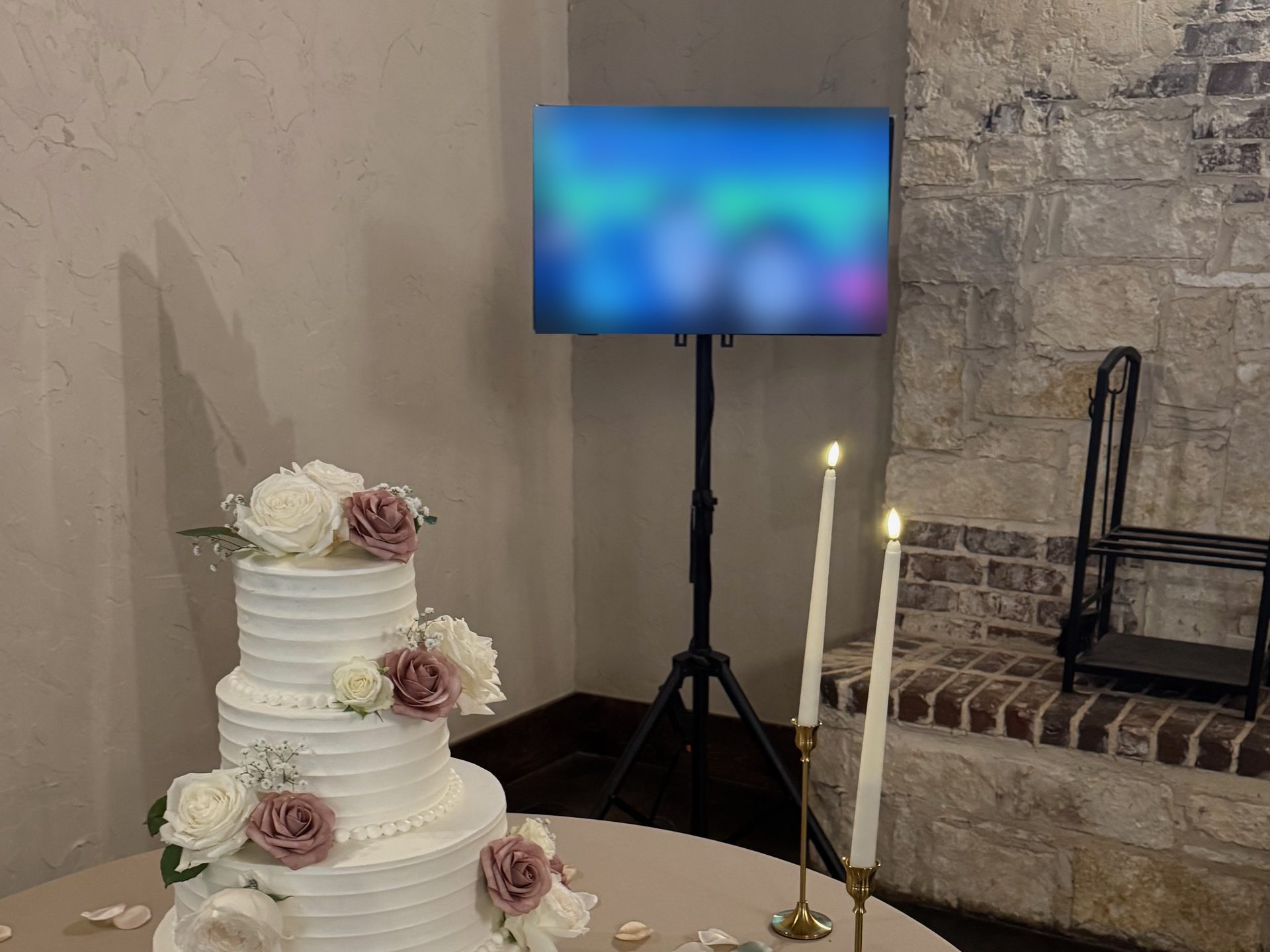 A wedding slideshow on a screen on a floor stand behind a cake table at a Dallas-Fort Worth reception