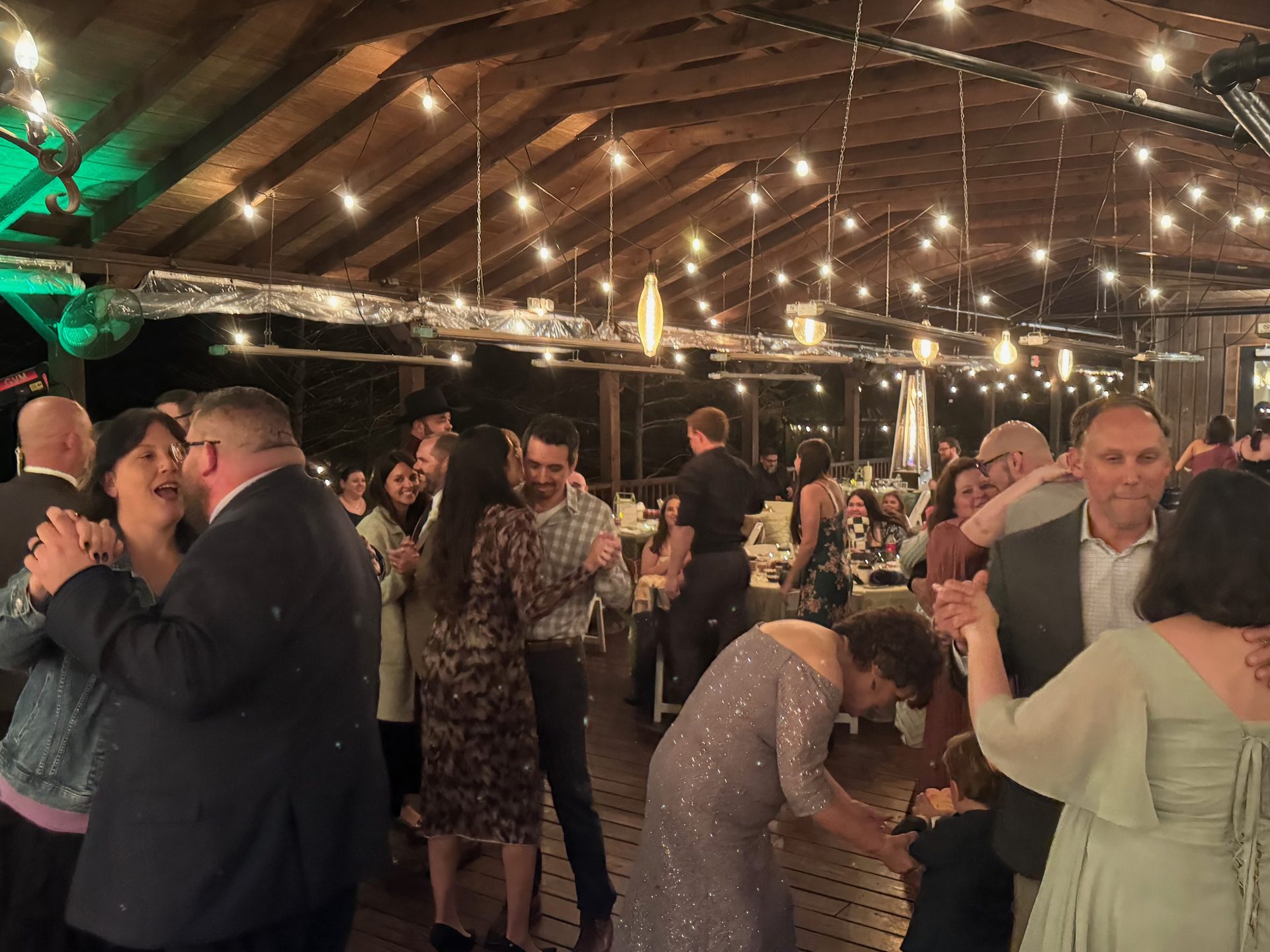 Guests dancing under a covered pavilion strung with lights at an outdoor Dallas-Fort Worth wedding reception