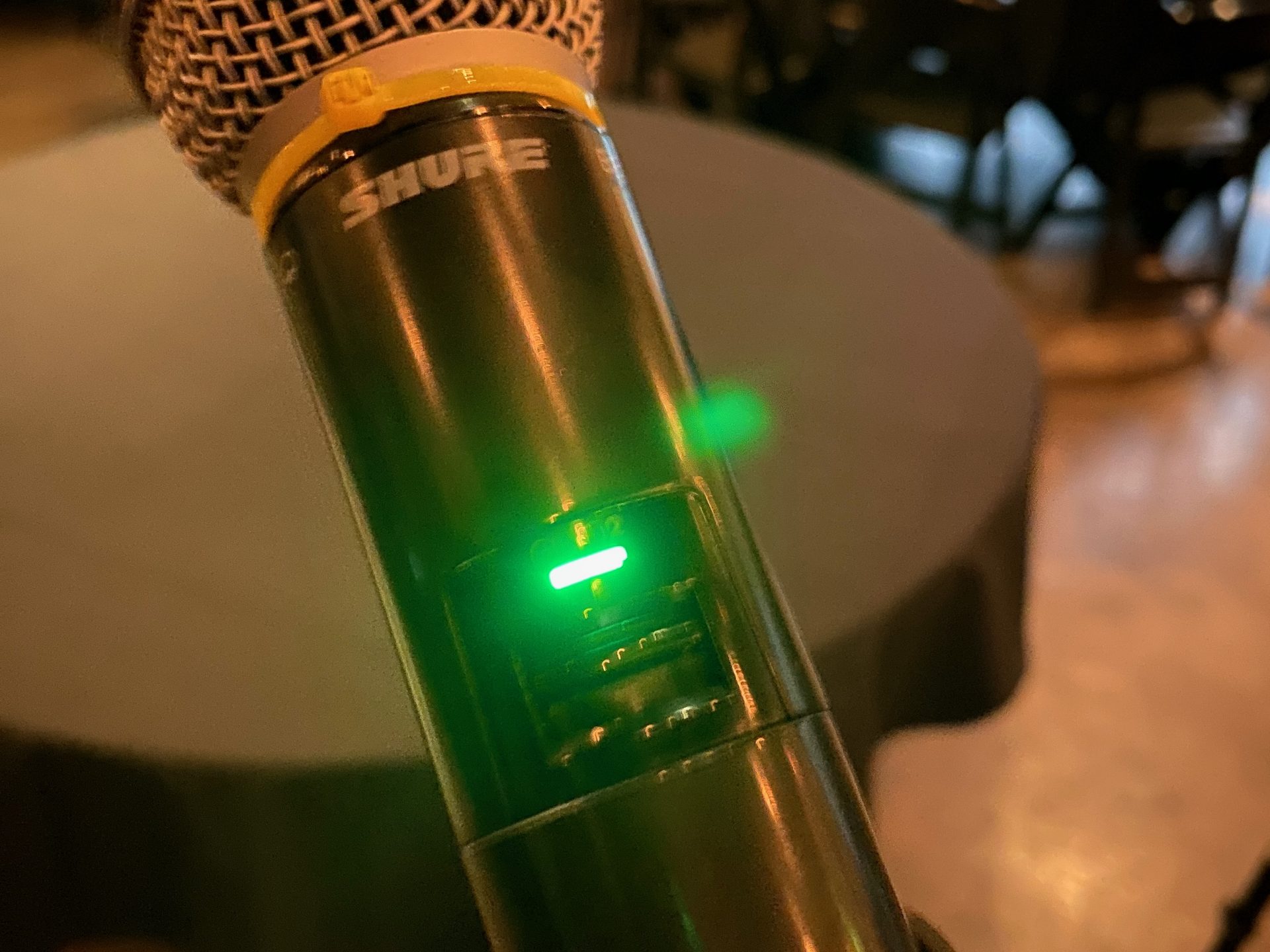 A Shure SLXD wireless handheld microphone showing a green ready light before a Dallas event